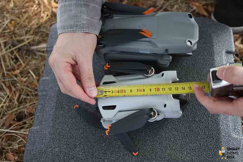 Die DJI Air 2S und die DJI Mini 3 Pro liegen zusammengefaltet nebeneinander und die Größe wird gemessen.